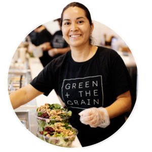 Green + the Grain staff smiling preparing a salad