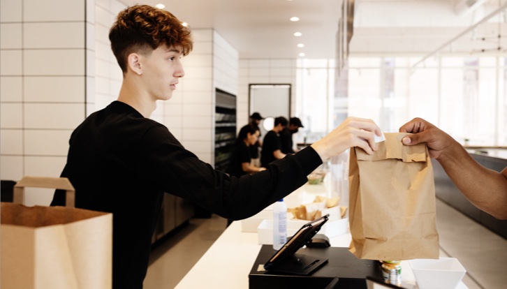 Cashier handing bag to customer